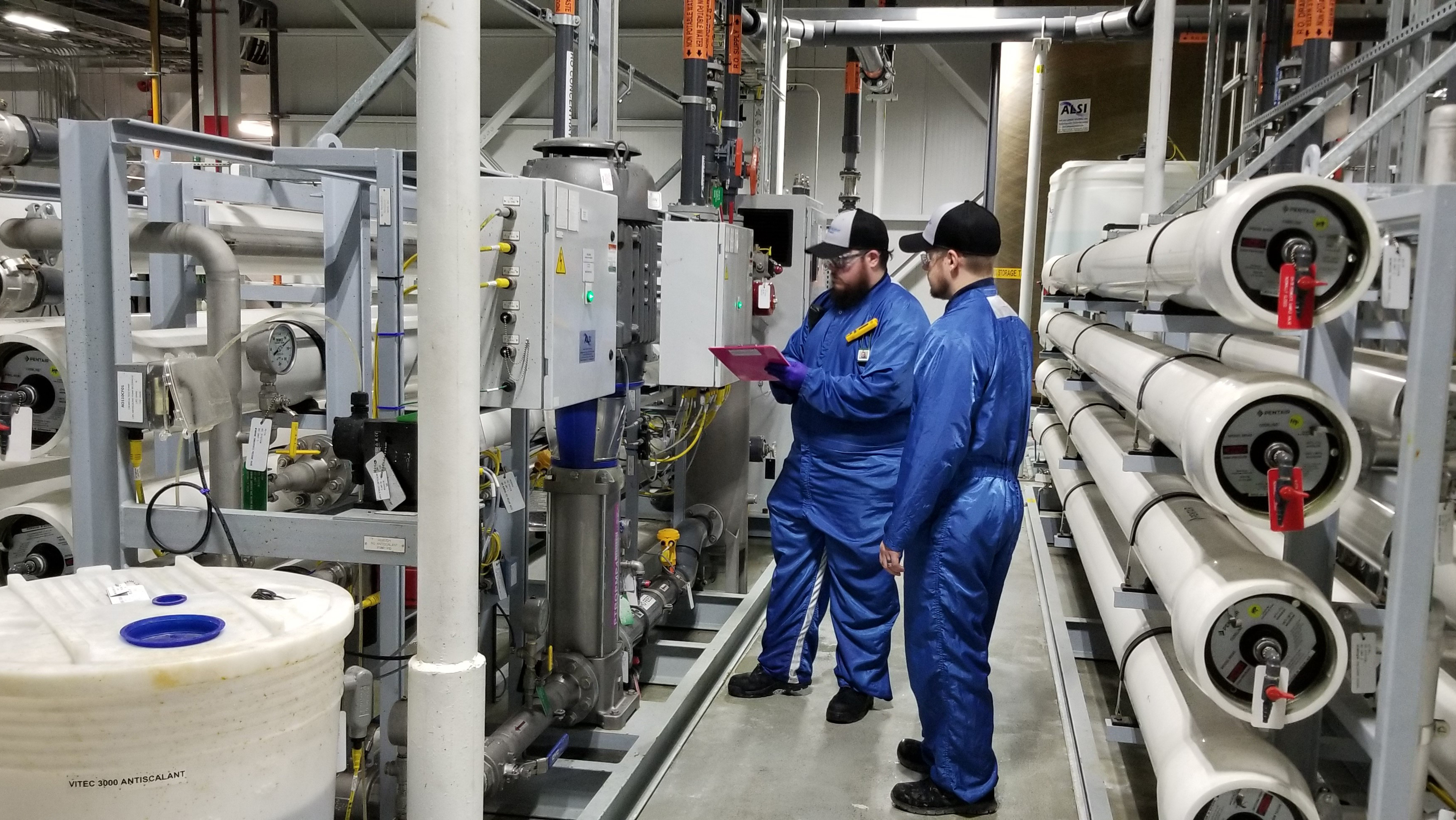 TBM RO过滤检查 Two men standing near reverse osmosis system in industrial plant checking machine