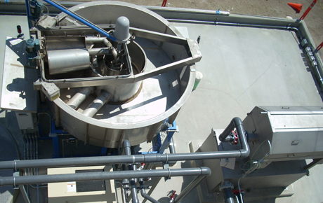 Wastewater treatment vents above a treatment facility with large pipes feeding into pumps.