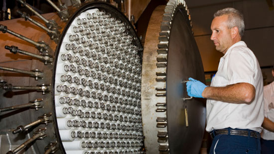 Industrial worker closing large cylindrical machine.