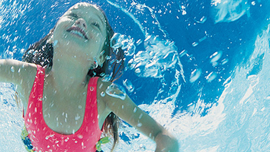 小女孩在干净的泳池里游泳 Young girl swimming in clean water at a pool in the summer sun.