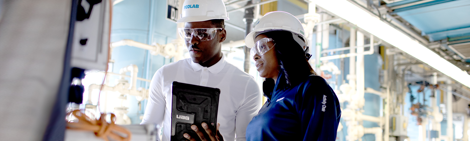 Two Ecolab experts reviewing data on a tablet computer at a power plant